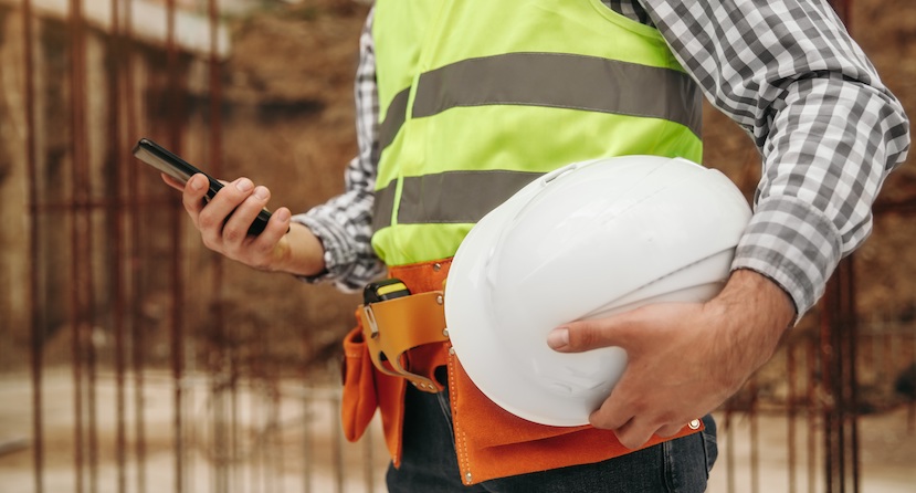 Construction worker on his phone holding a hat