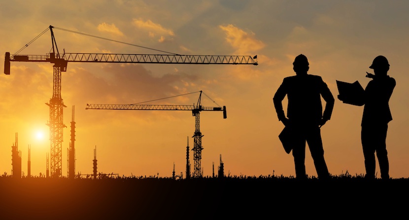 Two construction workers in front of a  sunset