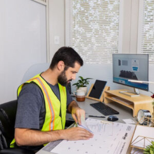 Male with beard wearing a fluorescent safety vest working at a desk